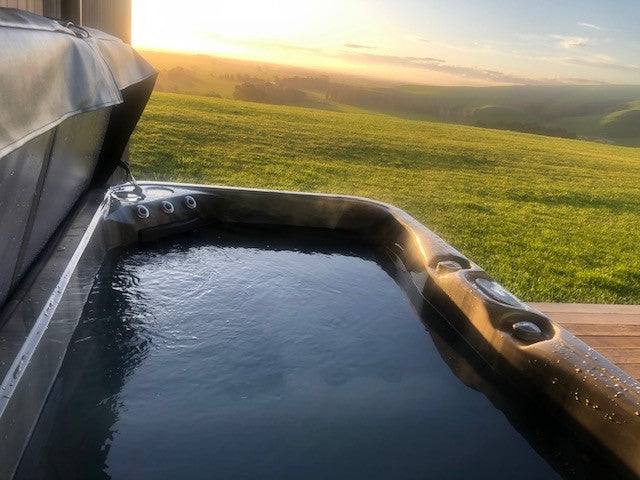 Sensation Azure 4 Person Spa Pool overlooking scenic landscape at sunset.