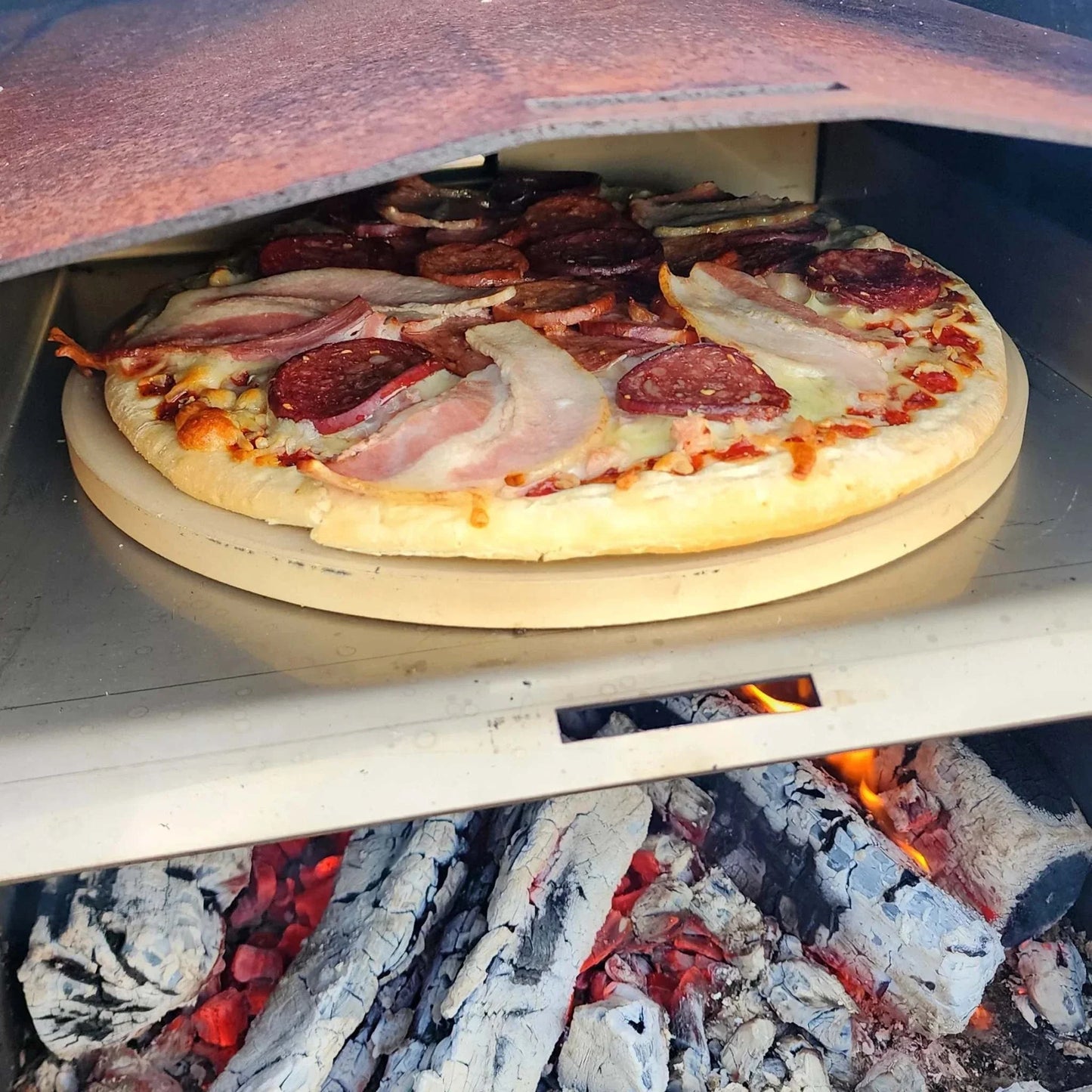 Pizza baking on Obelisk outdoor fire pizza kit with stone and peel.