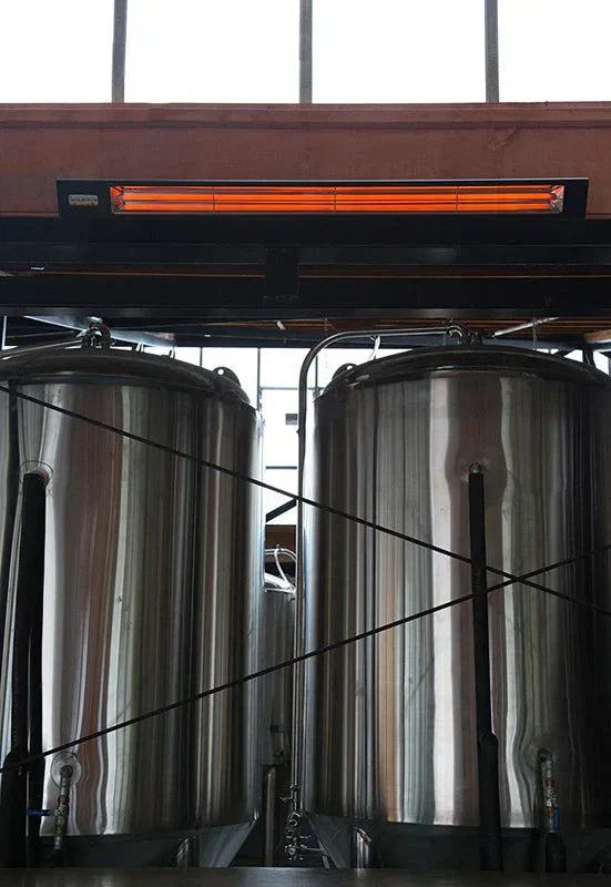 Infratech Slimline Shadow Heater in matte black housing installed above industrial tanks indoors.