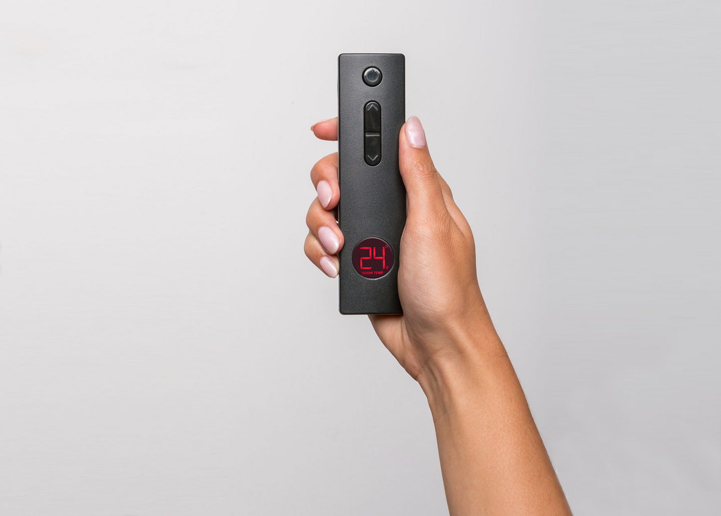 Hand holding a black remote control for Rinnai Evolve 1253 Plus gas fire.