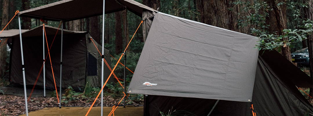 Oztent RV3 tent setup in forest with awning and orange ropes.