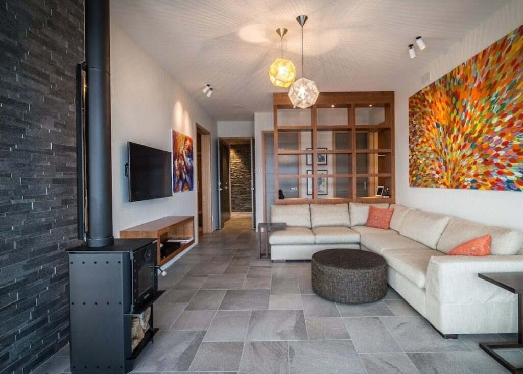 Contemporary living room with Warmington BLACK Studio 14 woodburner and 4.2m flue system, surrounded by modern decor and vibrant artwork.