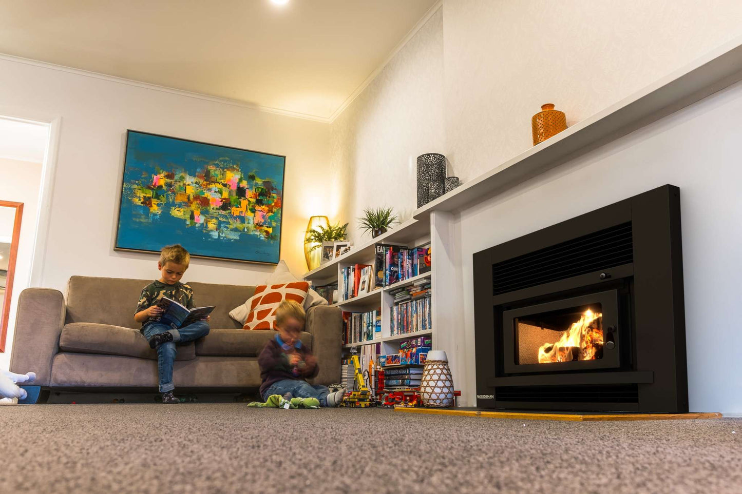 Children playing in a cozy living room with the Woodsman Totara Insert Fireplace providing warmth and ambience.