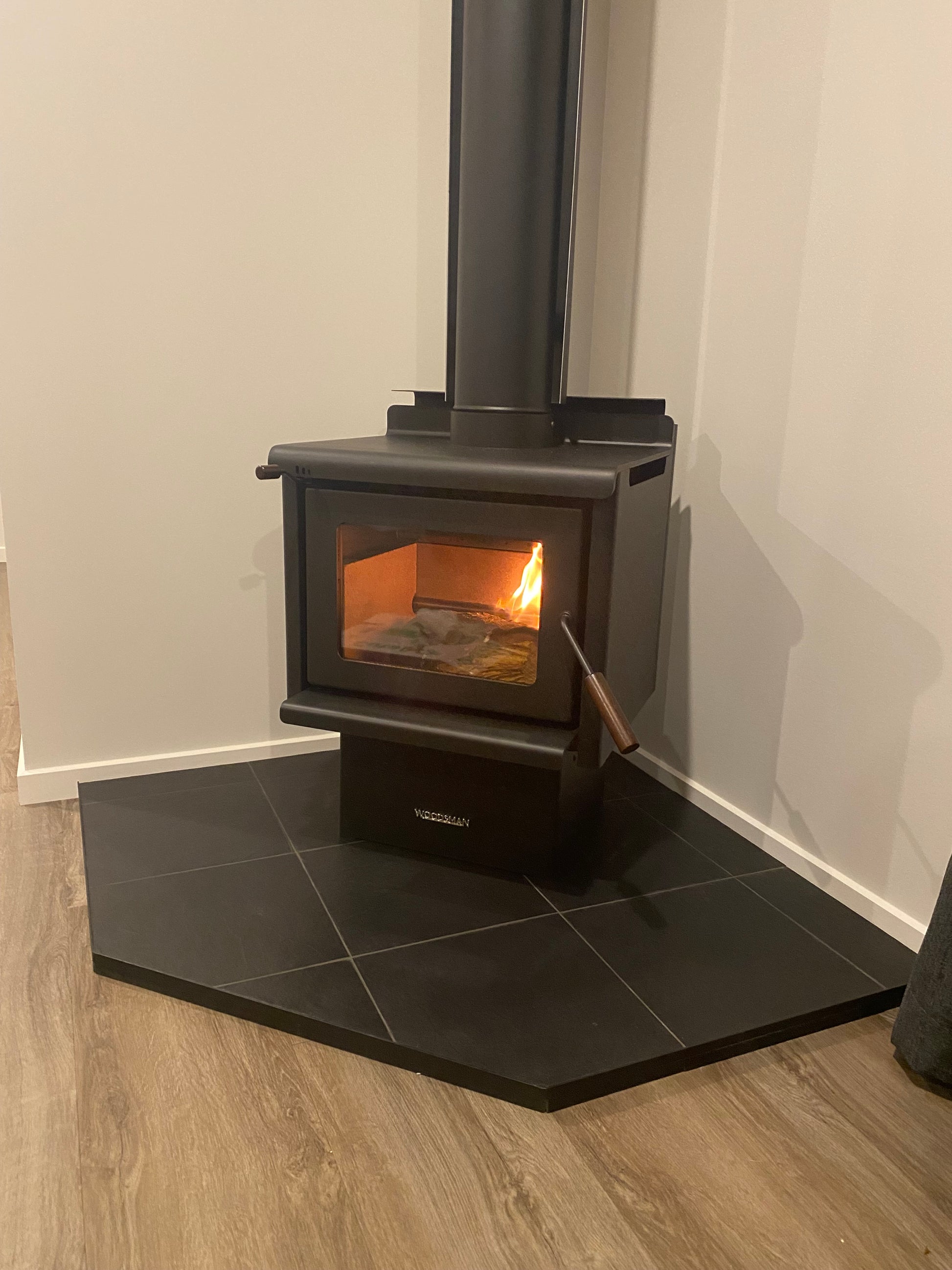 Modern kitchen hood with a light on, mounted above a stove.