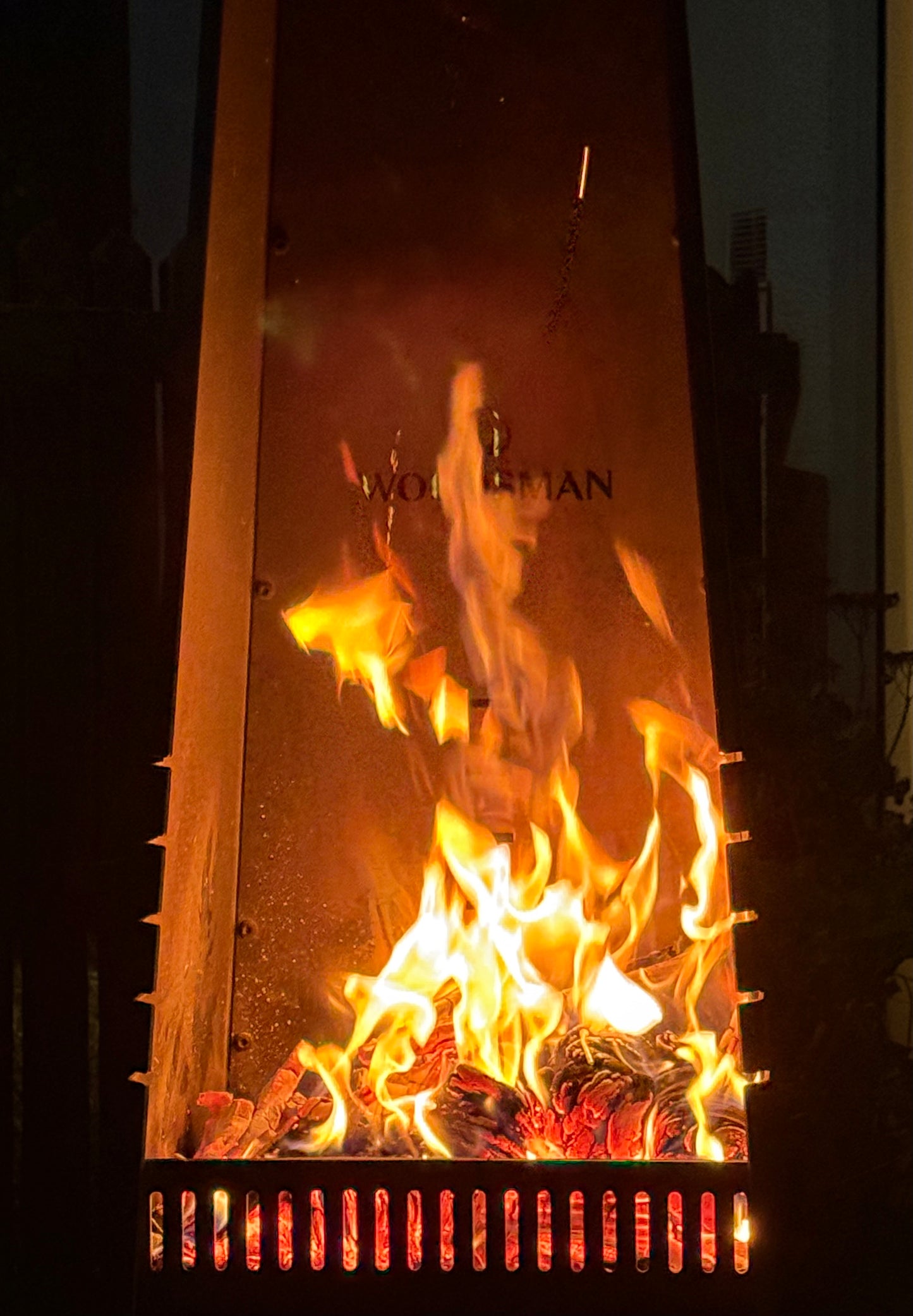 Fireplace with flames and 'Woodsman branding on a dark background