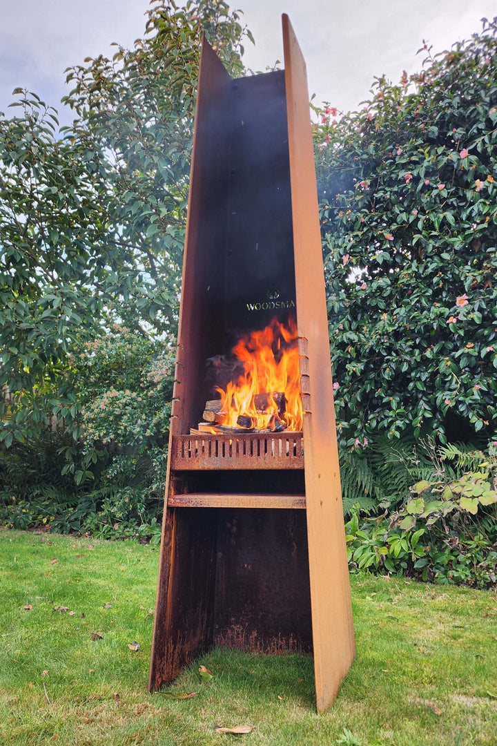 Woodsman Obelisk Outdoor Fire and BBQ in garden setting with flames.