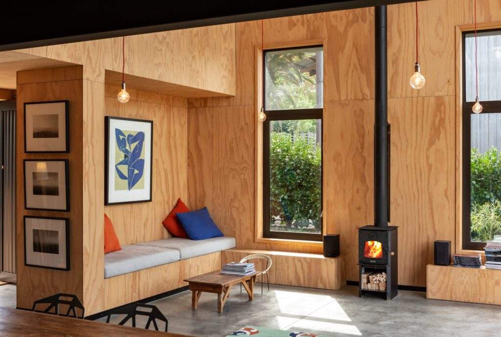 Warmington BLACK Studio 14 woodburner with flue system in a modern living room setting.