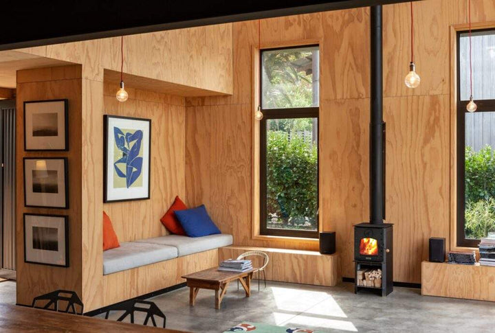 Warmington BLACK Studio 14 woodburner with flue system in a modern living room setting.
