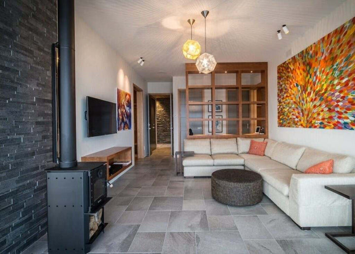 Contemporary living room with Warmington BLACK Studio 14 woodburner and 4.2m flue system, surrounded by modern decor and vibrant artwork.