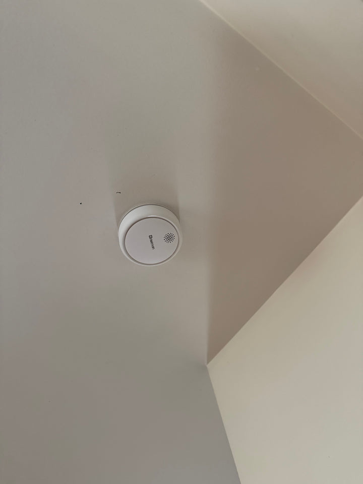White smoke detector on a white wall