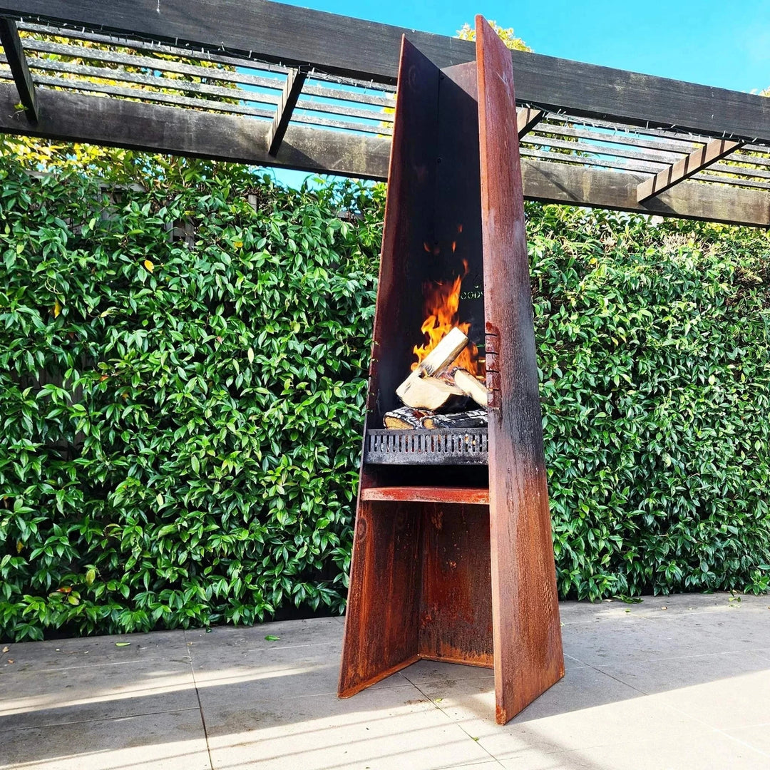 Woodsman Obelisk outdoor fire and BBQ with an elegant corten obelisk design in a garden setting.