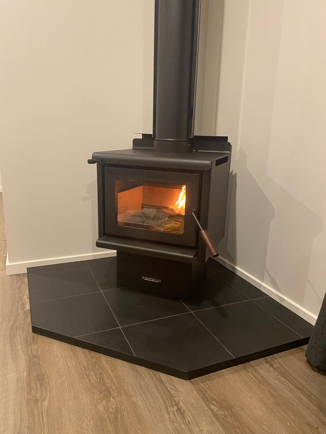 Modern kitchen hood with a light on, mounted above a stove.