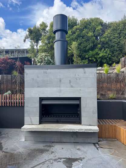 Outdoor stone fireplace with chimney against a blue sky