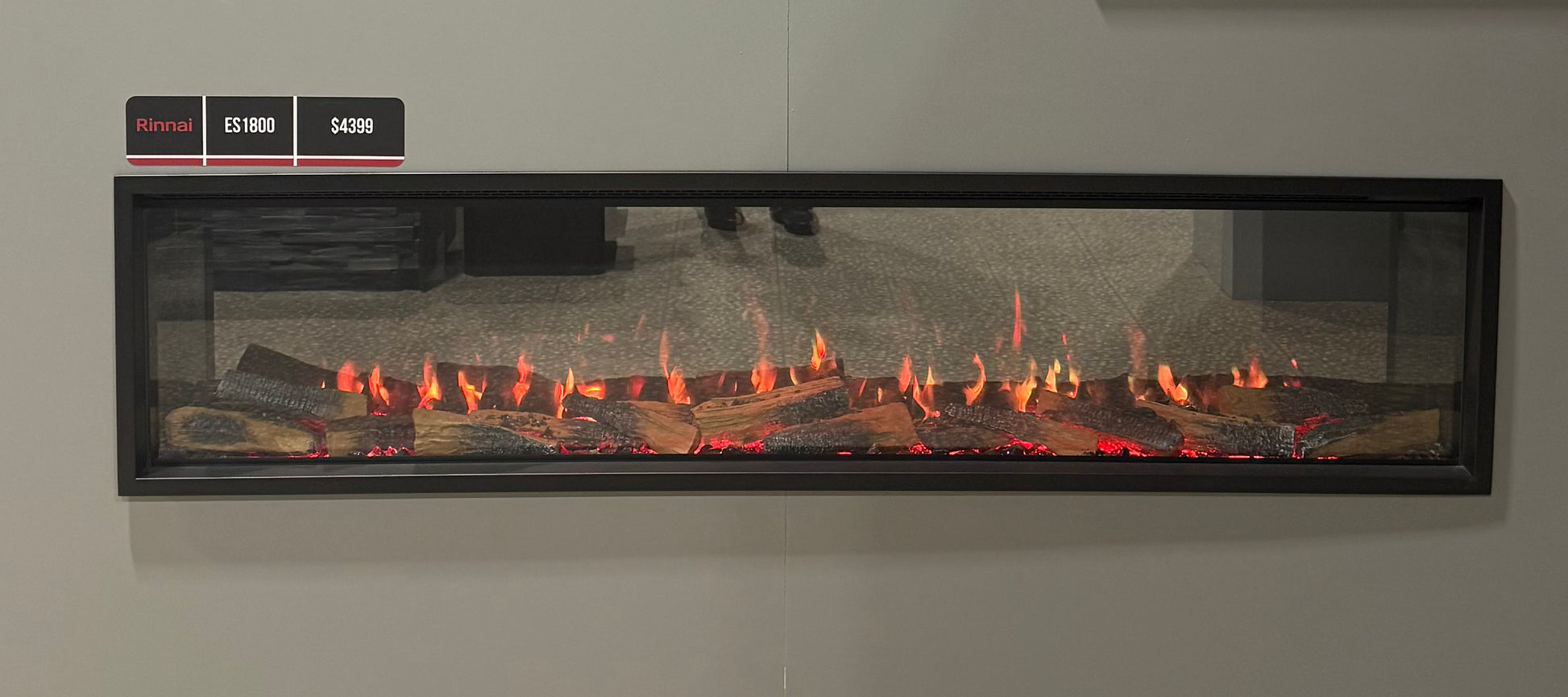 Modern electric fireplace with glowing embers on a gray wall