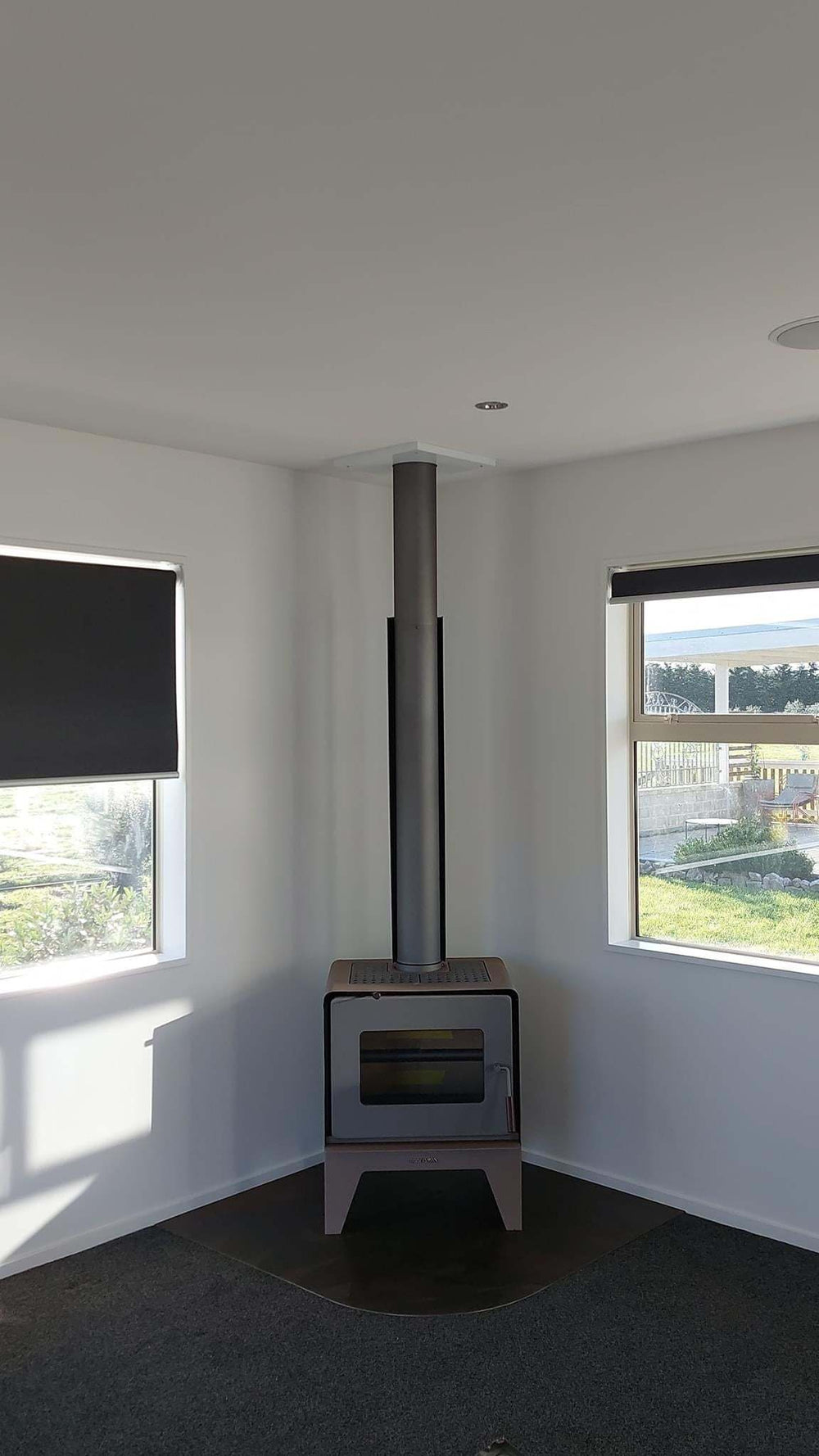 Woodsman Flare fire with leg base and 4.2m heatsaver flue system in brown/pewter, installed in a corner area.